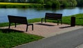 A wooden modern park bench with a metal embossed structure stands in a park by the river where cyclists stop for a snack on the ro