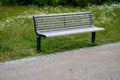 Wooden modern park bench with a metal relief structure on one leg stands in the park in rest areas and on paths made of a small Royalty Free Stock Photo