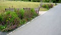 Wooden modern park bench with a metal relief structure on one leg stands in the park in rest areas and on paths made of a small Royalty Free Stock Photo