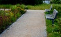 Wooden modern park bench with a metal relief structure on one leg stands in the park in rest areas and on paths made of a small Royalty Free Stock Photo