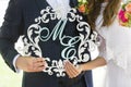 Wooden monogram of bride and groom in white and light blue colors in hands of bride and groom