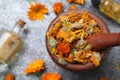 Wooden mortar with dry calendula flowers on light grey table, flat lay. Space for text Royalty Free Stock Photo