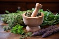 a wooden mortar with a mixture of herbs, with a pestle resting on top