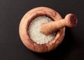 Wooden mortar with sea salt on black background