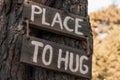 A wooden motivating tablet on an old pine tree in an autumn park says Ã¢â¬ÅPlace to hug