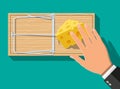 Wooden mouse trap with cheese and hand