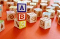 Wooden multicolored blocks with letters on orange background. Education for preschooler, reading, alphabet. Back to school concept Royalty Free Stock Photo