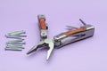 wooden multitool turned into pliers, knife, screwdriver on violet background, screws. repairing. fix