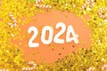 wooden number 2024 on christmas shiny Peach Fuzz background with sparkle festive golden confetti