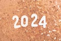 wooden number 2024 on christmas shiny Peach Fuzz background with sparkle festive golden confetti