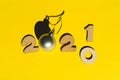 Wooden numbers 2021 chainging 2020 and a silver christmas ball on a yellow background.