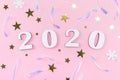 Wooden 2020 numbers and Christmas decorations, confetti, stars and snowflakes on pale pink background Royalty Free Stock Photo