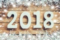 Wooden numbers forming the number 2018, For the new year and white snow with snowflakes on rustic wooden background. Royalty Free Stock Photo