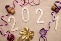 Light wooden 2021 numbers lie randomly on craft paper with champagne corks, packing tape, muzlet and gold bow Royalty Free Stock Photo