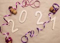 Light wooden 2021 numbers lie randomly on craft paper with champagne corks, packing tape and muzlet Royalty Free Stock Photo