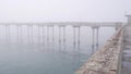 Wooden Ocean Beach pier in fog, misty calm boardwalk in haze, California coast.