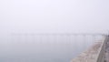 Wooden Ocean Beach pier in fog, misty calm boardwalk in haze, California coast.