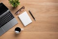 Wooden office desk table with blank notebook, laptop computer, cup of black coffee and supplies. Top view with copy space, flat Royalty Free Stock Photo