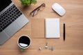 Wooden office desk table with blank notebook, laptop computer, cup of black coffee and supplies. Top view with copy space, flat Royalty Free Stock Photo