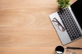 Wooden office desk table with laptop computer, cup of black coffee and supplies. Top view with copy space for text or design, flat Royalty Free Stock Photo