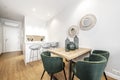 Wooden office table in an island kitchen with white marble top and gray veins and green velvet chairs