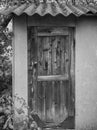 Wooden old door of a small house or barn. the roof is covered with slate. old rusty padlock. black and white