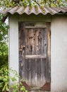 Wooden old door of a small house or barn. the roof is covered with slate. old rusty padlock. Royalty Free Stock Photo