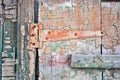 Wooden old door surface with rusty door hinge painted with green and sepia shabby paint Royalty Free Stock Photo