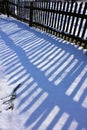 Wooden old fence shadow on snow Royalty Free Stock Photo