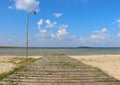 Wooden old ferny pier with vintage lamppost near the lake against blue summer sky