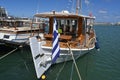 Wooden old style Greek yacht boat with white hulls and greek flag in the aft in port of Heraklion. Royalty Free Stock Photo