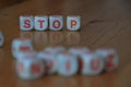 Wooden orange and white letter dice forming the word 'Stop' on wood background