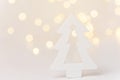 Wooden ornament Christmas tree in forest golden bokeh garland lights white background. New Years holiday magic atmosphere Royalty Free Stock Photo