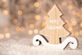 Wooden ornament cutout in the shape of a pine tree with text Merry Christmas and bokeh of yellow christmas lights with copy space Royalty Free Stock Photo