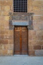 Wooden ornate door with geometrical engraved patterns on external old decorated bricks stone wall, Cairo, Egypt