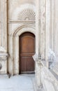 Wooden ornate door over white marble decorated wall