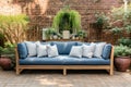 Wooden outdoor couch with blue and white textile cushions. Green potted plants. Georgian style residential house