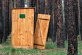 A wooden outhouse toilet with broken door