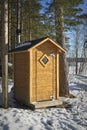 A wooden outhouse toilet in springtime