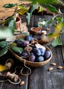 Wooden oval dish with juicy ripe plums on rustic wooden table