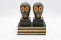 wooden owl bookends with open eyes standing on three black books isolated on a white background Royalty Free Stock Photo