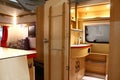 Wooden padded interior of modern Fendt Bianco campervan - detail of bathroom with sink and bedroom with TV on the left visible.