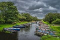 Wooden paddle boats moored in row on river surrounded by lush green trees Royalty Free Stock Photo