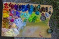 Wooden palette, mess of fresh squeezed bright colorful oil paints mixed in disorder, outdoor painting plein air, creativity Royalty Free Stock Photo