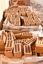 a wooden pallet plenty of old stacked red bricks in rows. Behind there is other pile of red bricks wrapped with plastic Royalty Free Stock Photo