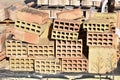 a wooden pallet plenty of old stacked red bricks in rows. Behind there is other pile of red bricks wrapped with plastic Royalty Free Stock Photo