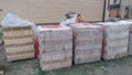 Wooden pallets with hollow bricks wrapped in polyethylene film stand on the grass near the cottage under construction Royalty Free Stock Photo