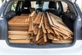 Wooden panels loaded into rear of white car with red workmans gloves in the foregorund