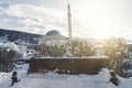 wooden park bench covered with snow in front of sinan pasha mosque at Prizren, Kosovo in winter season Royalty Free Stock Photo