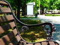 Wooden park bench detail with bus shelter in a distance Royalty Free Stock Photo